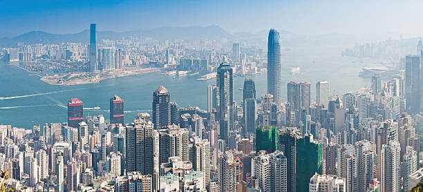 Hong Kong iconic skyscraper city crowded highrise harbour panorama China Dramatic panoramic vista across the crowded city blocks, towering skyscrapers and high rise apartment blocks overlooking Hong Kong Harbour towards Kowloon and the New Territories from Victoria Peak, China. ProPhoto RGB profile for maximum color fidelity and gamut. the bank of china tower stock pictures, royalty-free photos & images