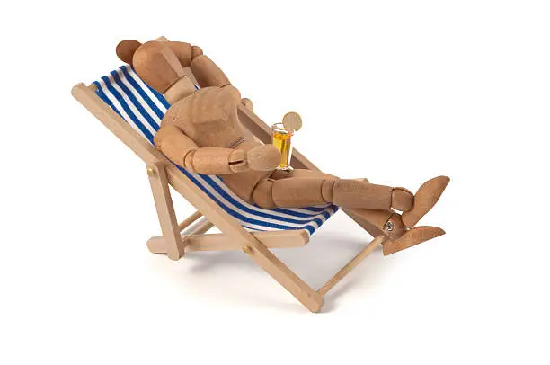 Wooden mannequin enjoys holiday or weekend, or balcony or garden... or ...? With drink in the hand. More of this lazy concept: