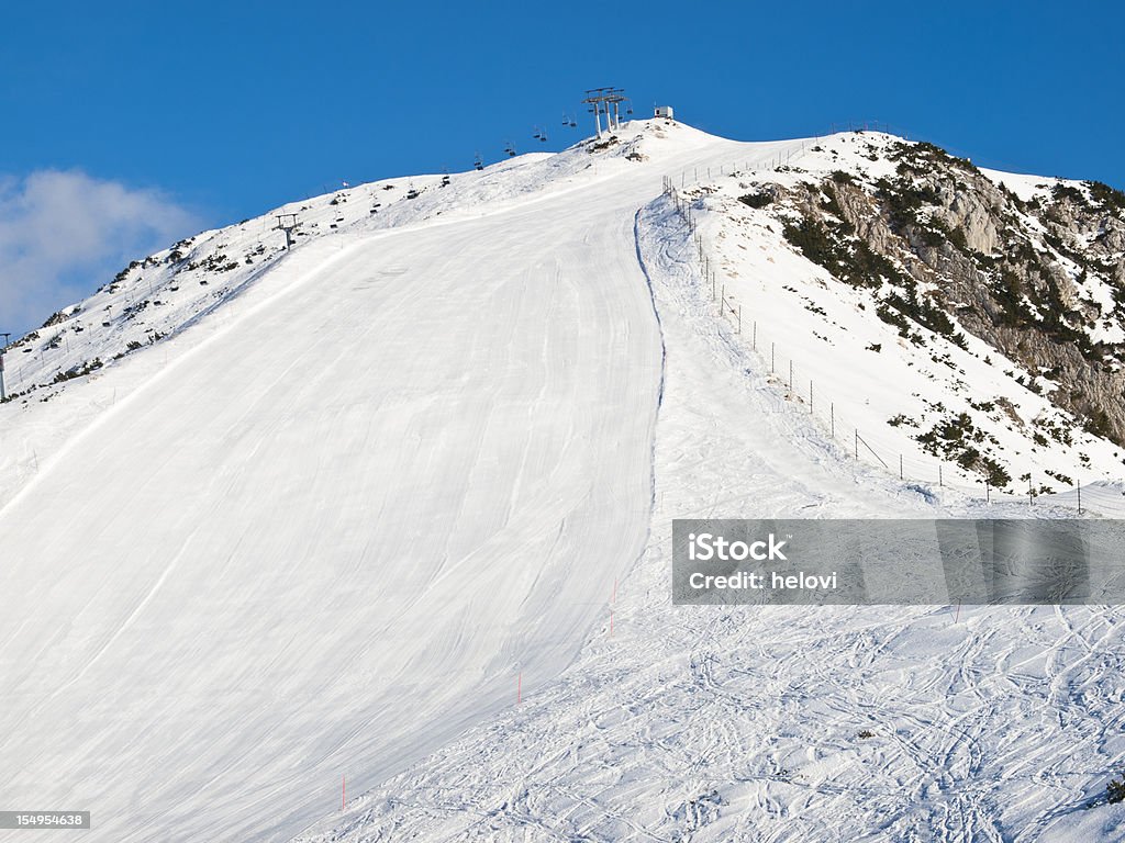 Skiing in mountains Freshly made ski track,lots of copy space. Slovenia.Skiing in high mountains, Beautiful white ski slopes, wide ski track in front view,  cold sunny  morning. Mountain Krvavec, Slovenia Alpine Skiing Stock Photo