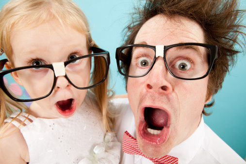 Color photo of a nerdy man and little girl both with big glasses and gasping with a look of surprise.