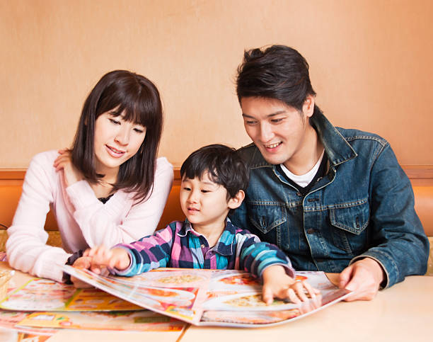 famiglia asiatica, guardare un menu del ristorante - bon appetite foto e immagini stock