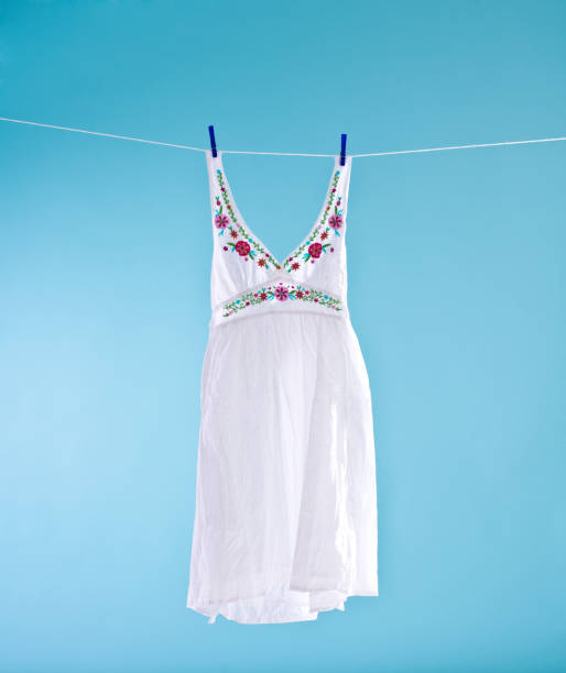 White dress White dress hanging out on a clothesline to dry. Blue background. Summer time. sundress stock pictures, royalty-free photos & images