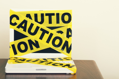 a computer laptop wrapped in caution tape with copy space.