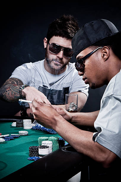 Playing poker. Two friends playing poker. Shot in study with black background. child gambling chip gambling poker stock pictures, royalty-free photos & images