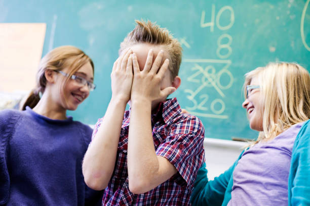 istock School boy hides his face while friends mock him 154956514
