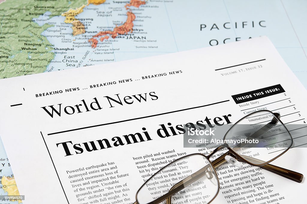 Tsunami Disaster news - III News concept related to tsunami and earthquake news. Map and the reading glasses on the newspaper. Tsunami Stock Photo