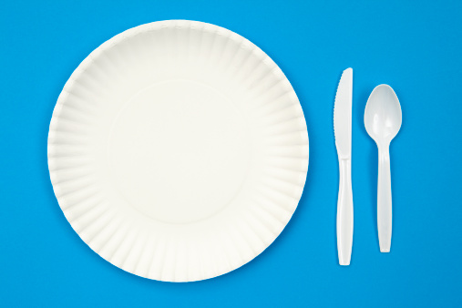 Paper plate and  plastic knife and spoon on a blue background.