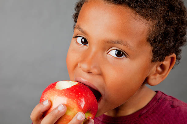 istock 8-year old African American boy eating apple 154956997