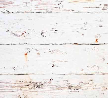 Close up showing rust from nails and a damaged and old paint finish on wooden planks.