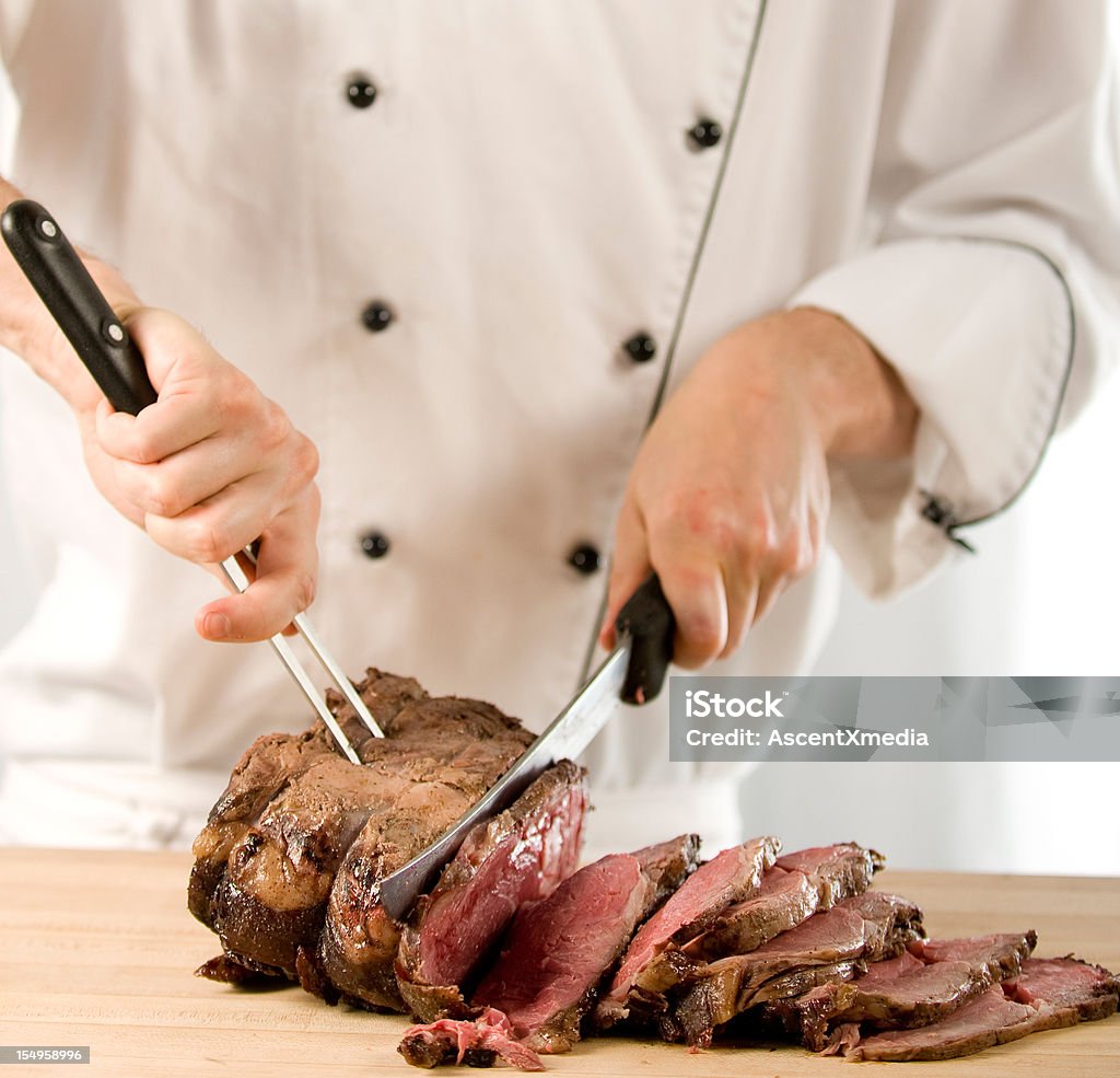 Chef carving perfectly cooked prime rib roast beef Chef carving a perfectly cooked juicy roast prime rib of beef Carving Food Stock Photo