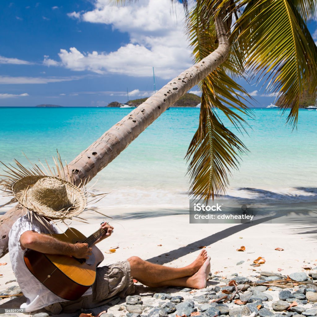 man playing guitar at a beach in the Caribbean unrecognizable man in straw hat playing guitar at a beach in the Caribbean Beach Stock Photo