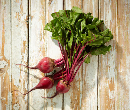 3 beets with greens shot in rustic farm stand setting.