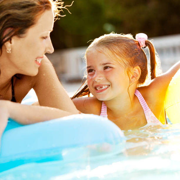 Mother and daughter having fun in pool stock photo