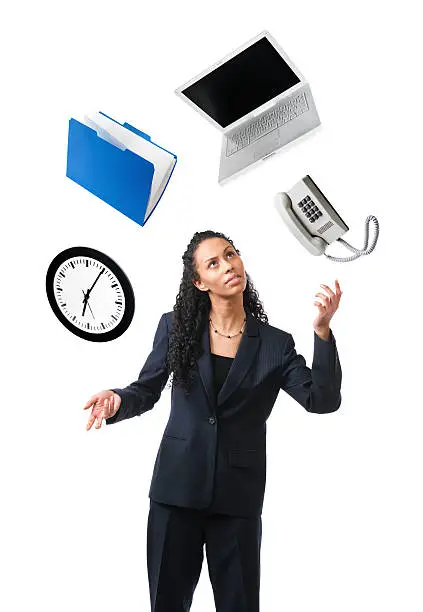A business person, a young, black businesswoman juggling and multi-tasking her work life, time and deadlines, represented by a clock, laptop computer, file folder, and desk phone. Isolated on a white background.