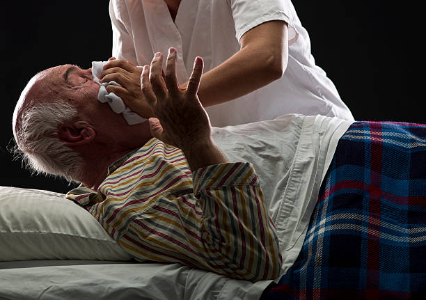 Euthanasia Nurse trying to suffocate her patient to death while he is sleeping on black background euthanasia stock pictures, royalty-free photos & images