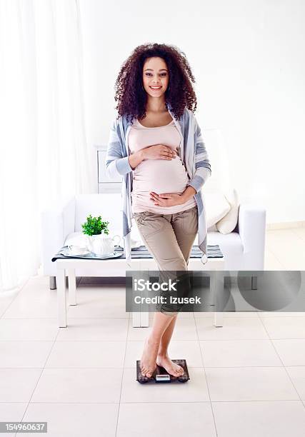 Smiling Pegnant Woman Weighting Herself Stock Photo - Download Image Now - Pregnant, Smiling, Vertical