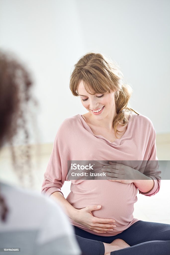 Great expectation A beautiful, pregnant young adult woman looking at her pregnant belly and cradling her unborn child. 20-24 Years Stock Photo