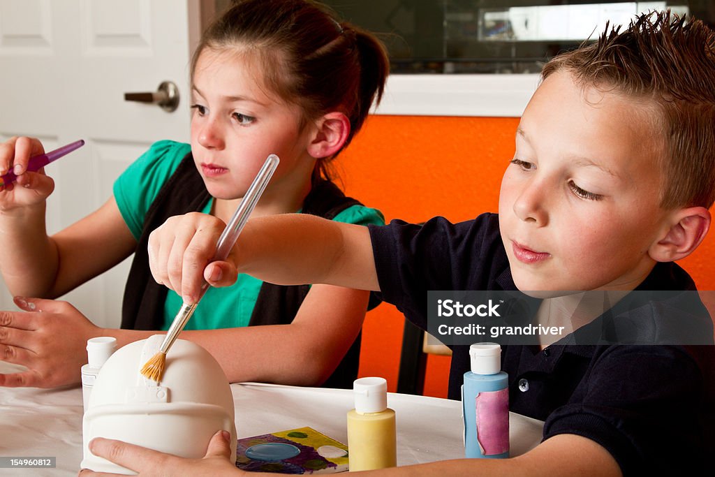 Ragazzo e ragazza dipingere ceramica - Foto stock royalty-free di Dipingere