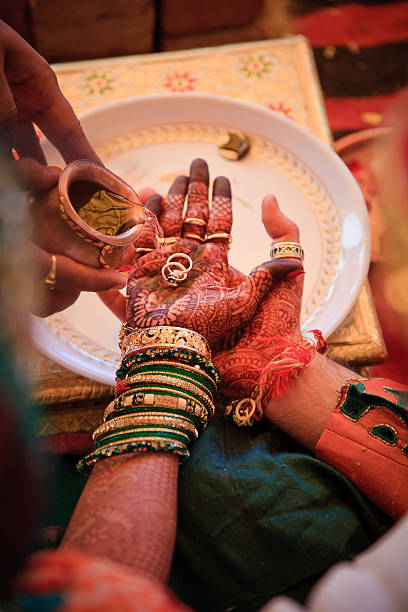 Indian bride and groom holding their wedding rings while the cleric pours holy water on their hands, during their wedding ceremony.