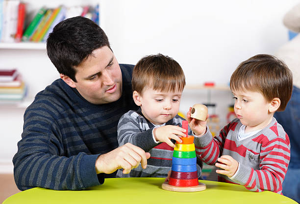 istock Father/ Carer Supervises Twin Boys Using Developmental Toy At Playtime 154961351