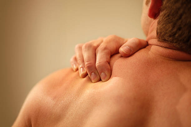 mann mit schulterschmerzen - shoulder pain physical injury muscular build stock-fotos und bilder