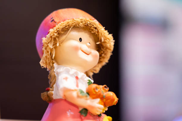 Ceramic baby girl doll sitting smiling bright bokeh light background.