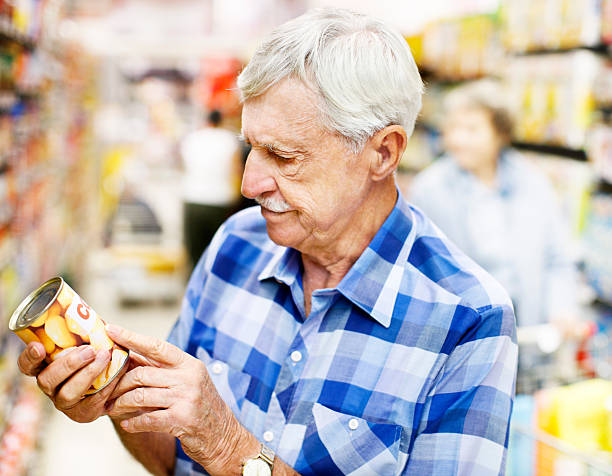 grave uomo anziano studi cibo etichetta in supermercato - senior adult aging process supermarket shopping foto e immagini stock