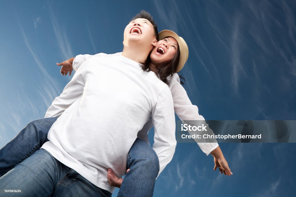 Felice asiatica coppia contro il cielo blu - Foto stock royalty-free di Portare a cavalluccio