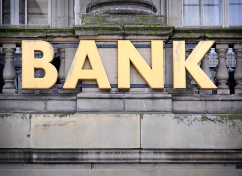 A large, gold sign on a building, with the word 'bank'.