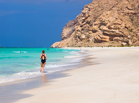 Senior lady jogging on  the  white sand at Shouab beach which is located on the west shore of island Socotra, Yemen.