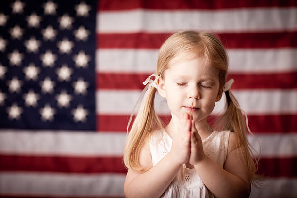 rapariga rezar na frente da bandeira dos estados unidos da américa - child flag fourth of july little girls imagens e fotografias de stock