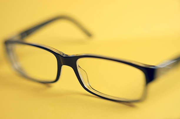 istock Blurred vision - Black Spectacles on yellow background, close-up 154962053