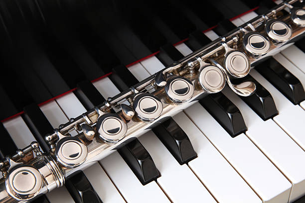 Flute Detail with Sheet Music - Musical instrument detail with selective focus on area of flute and sheet music notes in background. Pink accent light for colorful highlights.