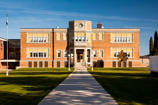 Ann Arbor, MI - August 2022: Students walking on the campus of the University of Michigan, Ann Arbor, with large auditorium building and clocktower