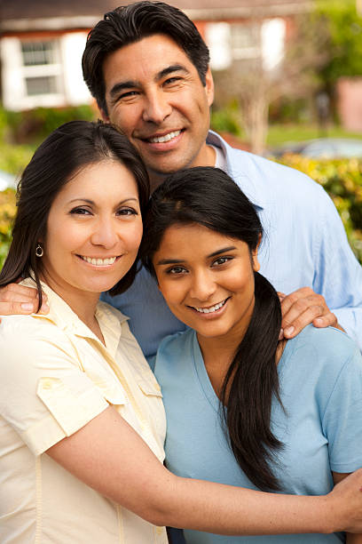 Happy Hispanic family hugging outside stock photo