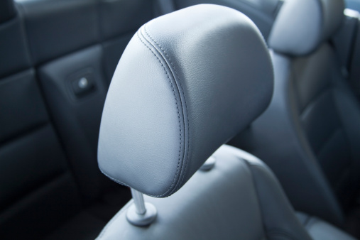 Closeup of a perforated leather seat with stitching detail in a modern sporty car.  Shallow focus.  Monochromatic.