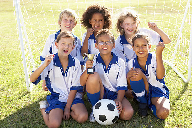Children In Soccer Team Celebrating With Trophy