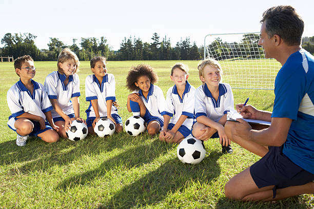 enfants dans l'équipe de football d'entraînement avec entraîneur - soccer player soccer men smiling photos et images de collection