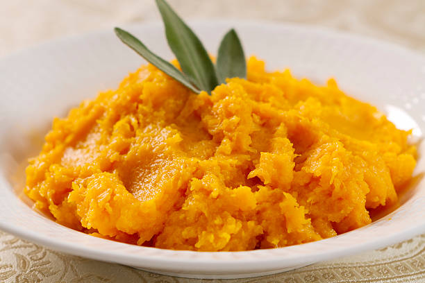 Butternut squash prepared in a white bowl A serving bowl of butternut squash, cooked and pureed with butter and maple syrup. mash food state stock pictures, royalty-free photos & images