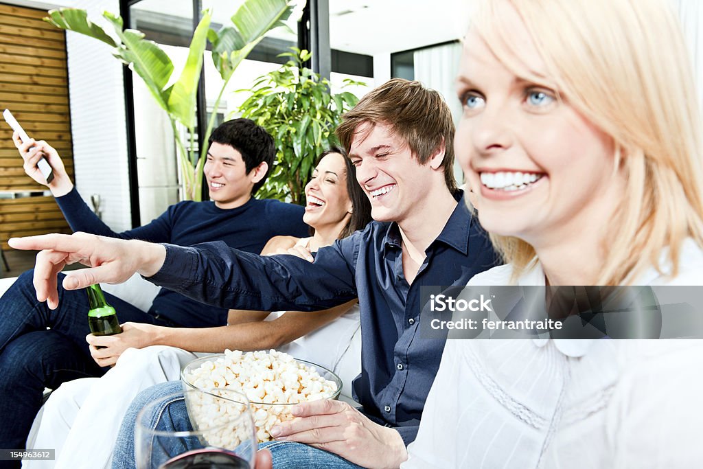 Group of friends watching TV and laughing Group of friends watching TV and laughing out loud 20-29 Years Stock Photo