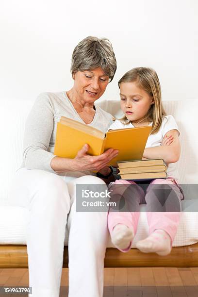 Senior Woman Reading To Little Girl Stock Photo - Download Image Now - 6-7 Years, 60-69 Years, Adult