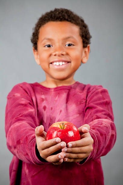 istock 8-year old African American boy giving an apple 154963898