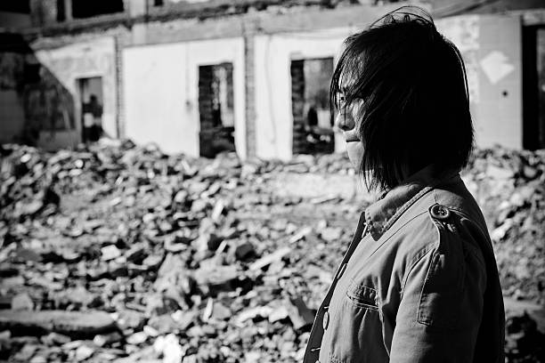 Homeless Woman Crying - XLarge A sad asian woman is standing on the ruin of her house bomb photos stock pictures, royalty-free photos & images