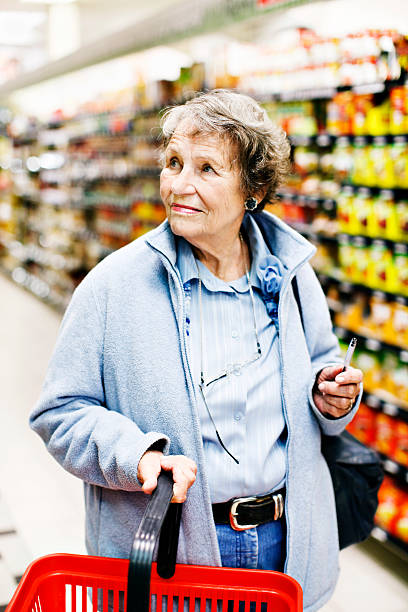 senior donna shopping nel supermercato look tutto, confusa - senior adult aging process supermarket shopping foto e immagini stock