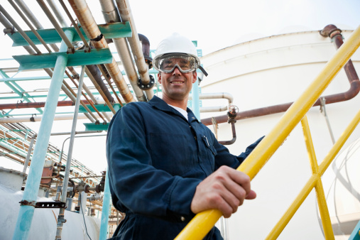 Mid adult man working at manufacturing plant, standing by storage tank