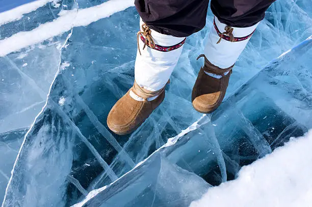 Traditional mukluks on the ice of Great Slave Lake in Canada's Arctic.  The ice here is more then one metre thick.  The ice is clear blue in colour with good copy space.