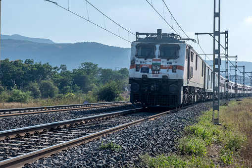Pune, India - March 26 2023: Passenger Train hauled by a WAP7 loco heads towards Pune, at Kamshet near Pune India.