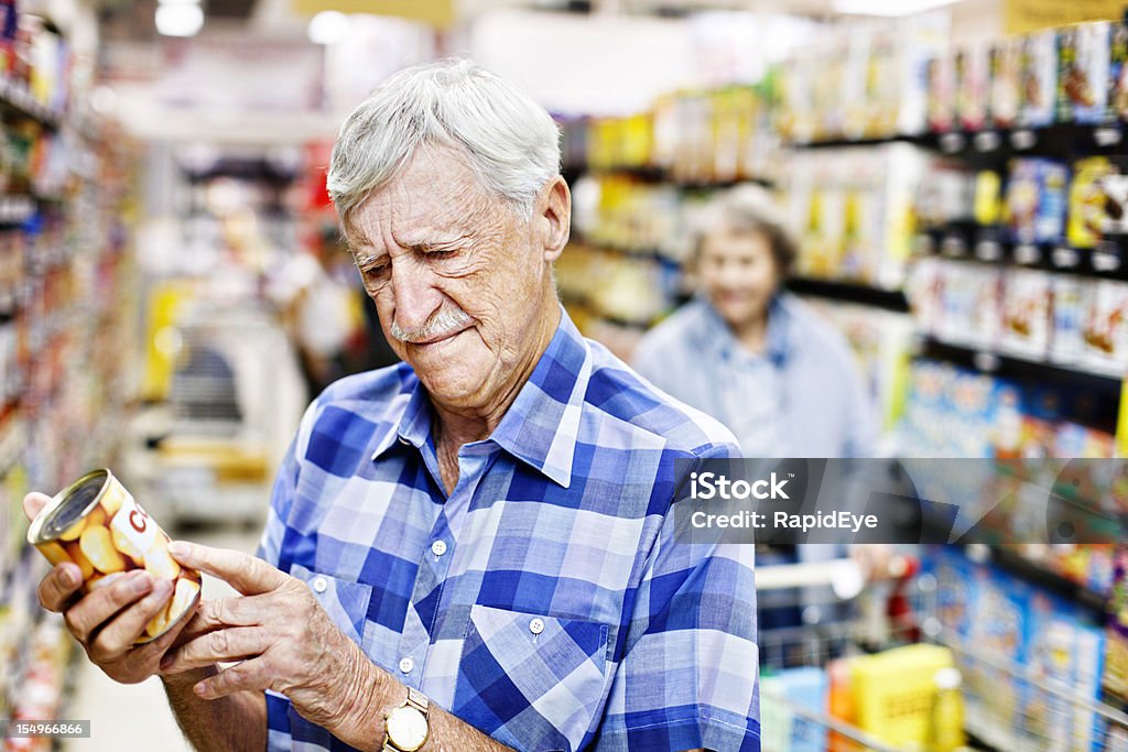 Preocupado homem sênior cheques pode label no supermercado - Foto de stock de Supermercado royalty-free