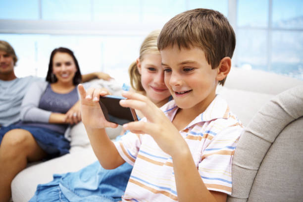 istock Young kids looking at cell phone with parents in background 154967515