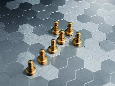 The golden pawn chess piece team standing as a arrow shape on hexagon pattern board floor background. Leadership, teamwork, fellowship, planning, uniqueness, and business growth and success concepts.